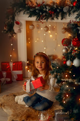 Happy little girl near fireplace at Christmas eve