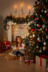 Happy little girl near fireplace at Christmas eve