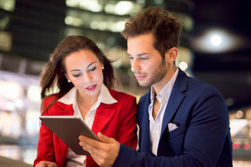 Business people using a tablet at night