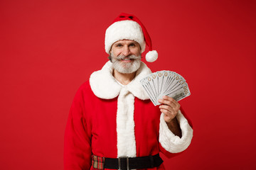 Smiling elderly gray-haired mustache bearded Santa man in Christmas hat isolated on red background....