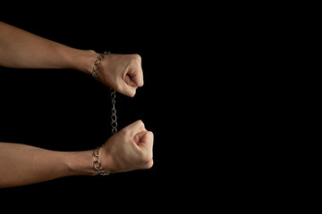 person with fetters on hands isolated on a black background with copy space. breaking chains...