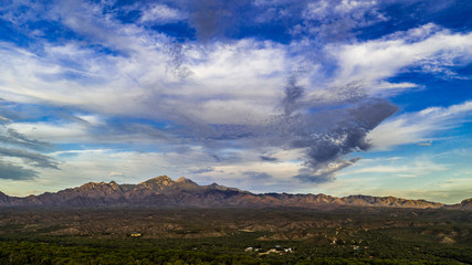 Obraz na płótnie Canvas Sunset, aerial landscapes of Santa Rita Mountains from above Tubac, Arizona with warm , golden plains, purple mountains, blue sky with colorful clouds on a Fall day 