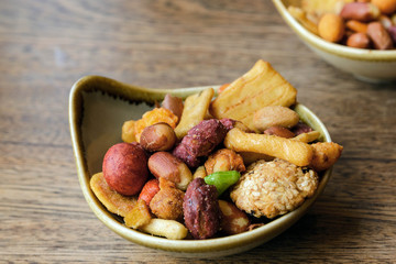 Nuts and cookies seasoned with salt and spices in a small plate on a wooden table. Great beer snack. Spicy snacks.