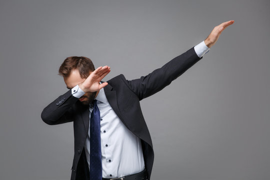 Young bearded business man in classic black suit shirt tie posing isolated on grey background studio portrait. Achievement career wealth business concept. Mock up copy space.Showing DAB dance gesture.