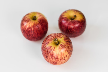 Fototapeta na wymiar Fresh red yellow striped apples with water droplets on a white glossy kitchen table. Tasty bright juicy fruits. Healthy eating Isolated object