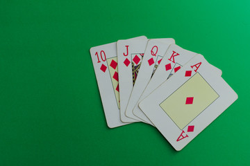 Royal flush of diamonds cards of a poker deck over a green background