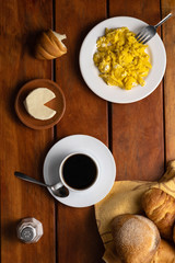 Obraz na płótnie Canvas Breakfast with coffee, cheese and scrambled eggs, served on a wooden table, different types of bread and sweet empanadas with cheese