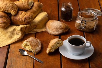 Classic breakfast of Ecuador, served on a wooden table with a cup of coffee and sweet cheese bread, brown sugar, soluble coffee and more bread