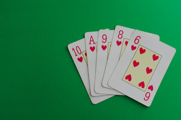 Flush of hearts cards of a poker deck over a green background