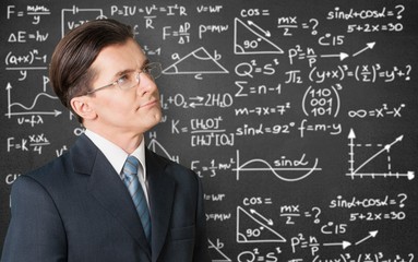Cute little schoolgirl in glasses on blackboard background