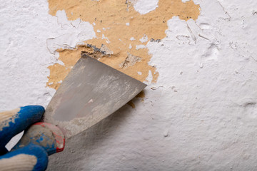 Removing old paint from the wall with a metal spatula. Small painting works at home.