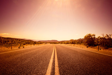 Desolate desert road with mountains with sunflare; western United Stated