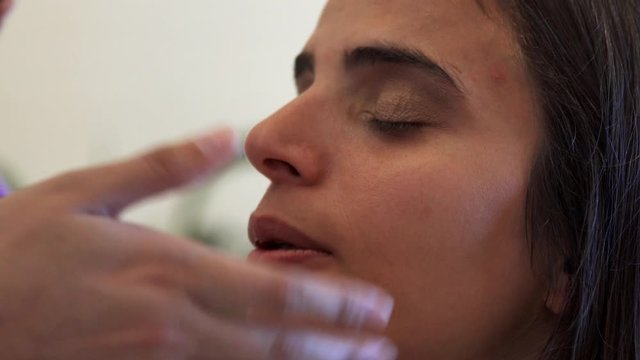 Make up artist applying eye make up with her fingers and brush