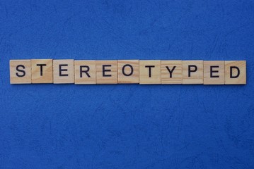 word stereotyped made from brown wooden letters lies on a blue table  