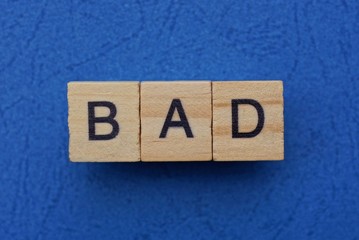 word bad made from brown wooden letters lies on a blue table  