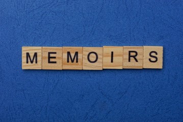 word memoirs made from brown wooden letters lies on a blue table  