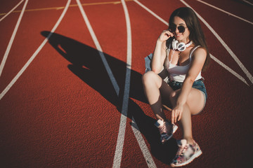 Obraz na płótnie Canvas Stylish woman posing for the camera sitting on running track.