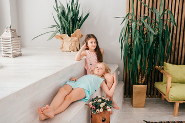 Two funny and beautiful model girls hugs and embrace in interior studio with decorations.
