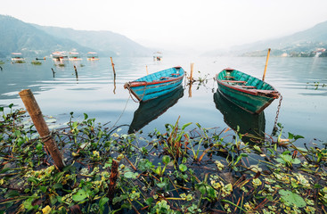 Multicolored traditional rowboats on the morning lake water at LakeSide in Pokhara, Gandaki Pradesh, Nepal. Asian traveling concept image.