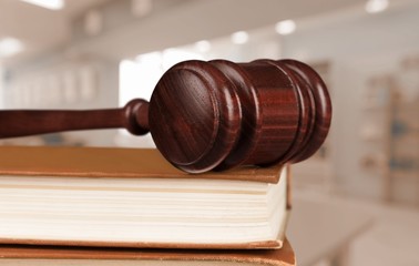 Books and wooden judge gavel on old wooden table.