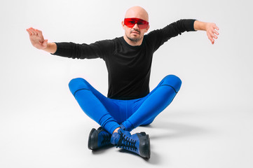 Strange man in stylish clothes and red sunglasses relaxing in studio against white background.