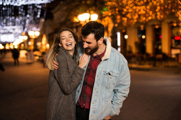 Happy young couple walking in a beautiful city in the evening