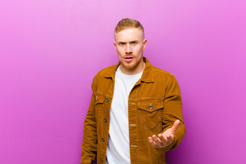 young blonde man looking angry, annoyed and frustrated screaming wtf or what‚Äôs wrong with you...
