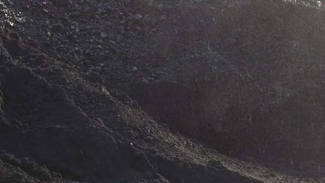 Coal heap close up. Pour drops of water onto a coal pile. Rain at the coal terminal.