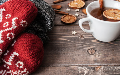 winter flatlay with cozy home sweater, mittens, cup of black tea and spices for mulled wine
