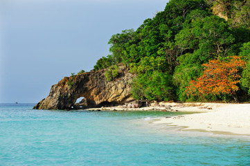 Naklejka premium Talu Island. Koh Talu in Tarutao National Park of Satun province Thailand. Mountain and beach with blue sky cloudy. Cave entrance. Cave hole inside. Mountain hole. Sea and mountain hole