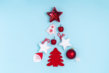 New Year and Christmas composition in the form of chrismas tree. Red and white decorations - stars, christmas balls, toys on pastel blue background. Top view, flat lay, copy space