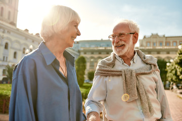 I feel so happy with you. Portrait of cheerful beautiful senior couple looking at each other with smile while walking together outdoors on a sunny day