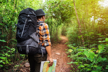 man traveler with backpack and map in the forest