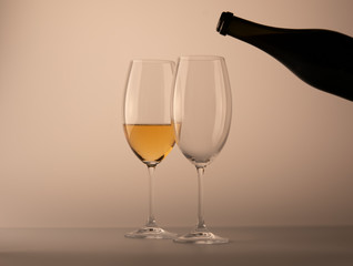 Two wineglass one half full of white wine black bottle white background
