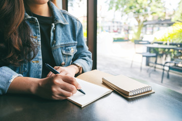 Closeup image of a woman writing on a blank notebook on the table