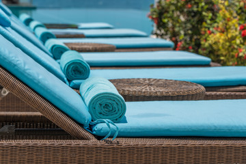 Closeup of towels on lounge chairs near a luxury swimming pool at a tropical resort spa in island...