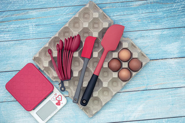 Flat lay view of cake making baking utensils, raw eggs and accessories on blue rustic background