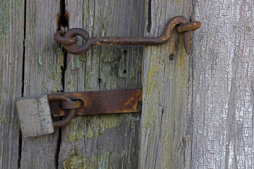 Old and rusty hook locks the old dried up wooden barn door. Old wooden door with locker, close-up, full frame.....