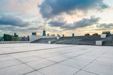 Empty square floor and modern cityscape in Shanghai at sunset.