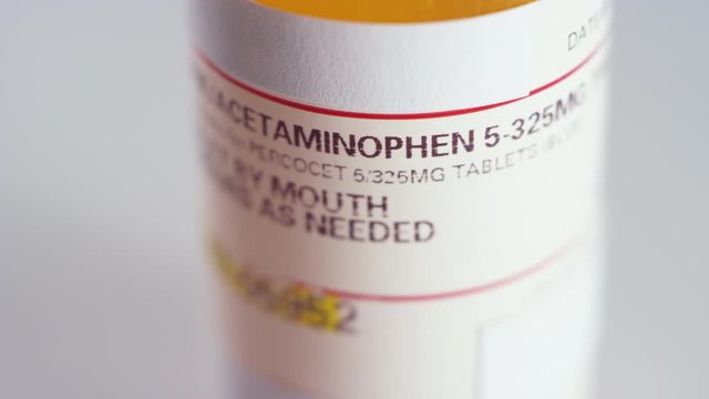 Extreme close-up of a spinning bottle of oxycodone pills label on a white background