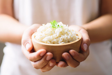 Cooked rice with quinoa seed in bowl holding by hand