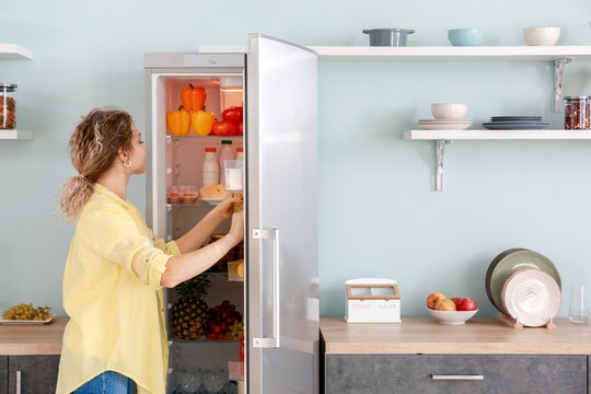 Woman Choosing Food In Modern Fridge At Home