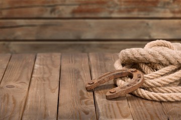 Old horseshoe, lariat lasso and cowboy hat on background