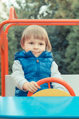 Fototapeta na wymiar Happy preschooler playing with toy car on playground in park. Child development concept