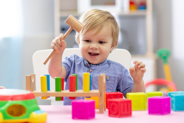 cute toddler baby boy playing with wooden hammer block toy