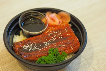 Unadon or unagi donburi with Pickled Ginger in Black Plastic Bowl for Take home.