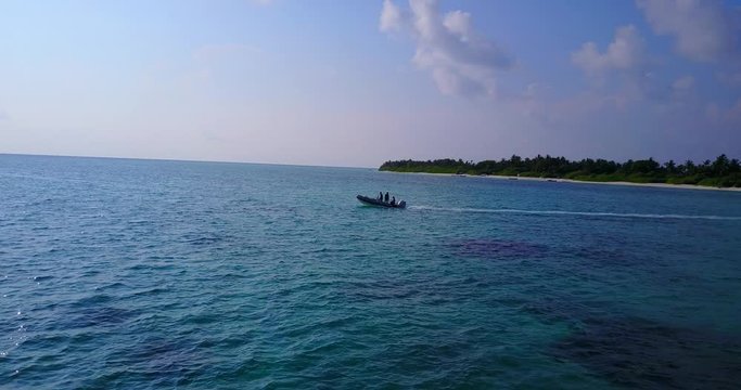 Motor boat leaving shore of tropical island in Hawaii, sailing toward open blue azure sea under a cloudy sky early morning