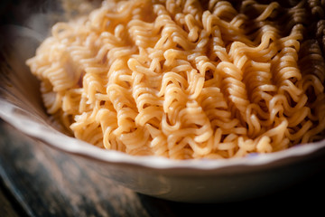 The smoke was poured from the boiled instant yellow noodles that had been boiled in hot water and brought out from a boiling pot in a bowl to be prepared as a food menu.