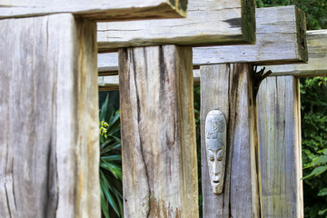 Carved out wooden religious mask of aboriginal symbol decorated among wooden planks