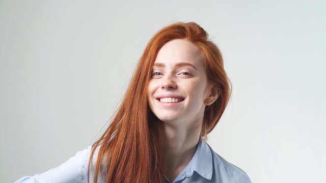 Happy beautiful girl with curly red hair smiling looking at camera over white background.